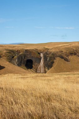 Dağlar yosun, ot ve liken ile kaplıdır. Sonbaharda güneşli güzel bir gün, altın otların rengini parlatıyor. Fjadra nehri bölgesi, Güney İzlanda, Kirkjubaejarklaustur yakınlarında..