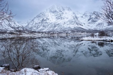 Coast of the Norwegian sea. Mountains in the background. Land covered by snow. Cloudy sky in the late autumn. Laupstad, Norway. clipart