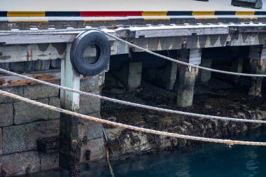 Tekneler için üç ip ve onları korumak için de eski bir lastik. Norveç 'in Narvik limanında rıhtım.