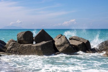 Tyrhenian (Akdeniz) denizinin sakin turkuaz suyu. Yapay ve doğal dalgalar. Suyun Horizon 'u ve kumlu plaj. Baharda beyaz bulutlu mavi gökyüzü. Spadafora, Sicilya, İtalya.
