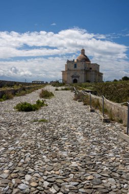 İlkbaharda Milazzo Kalesi 'nin (Castello di Milazzo) çevresindeki Eski Katedral' in (Duomo Vecchio) inşası. Mavi gökyüzü, beyaz bulutlar. Milazzo, Sicilya, İtalya.