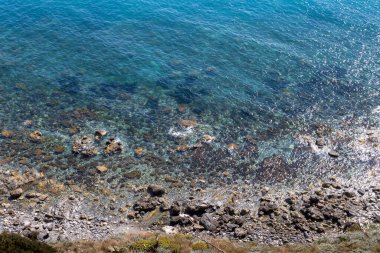 Tyrhenian (Akdeniz) denizi ve kıyı kayalarının sakin, şeffaf sularının parlak, koyu turkuaz renginde bir tepeden manzarayı izleyin. Milazzo, Sicilya, İtalya.