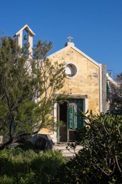 Küçük terk edilmiş kilise. Sarı ön duvarda eski yıpranmış bir kapı var. Tepesinde basit bir tahta haç ve çan kulesi. Vahşi bahçeyle çevrili. Caldera, Sicilya, İtalya.