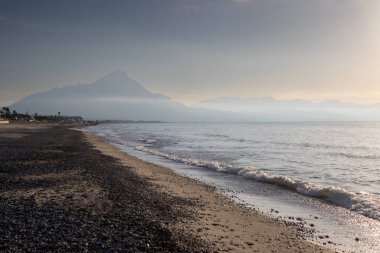 Çakıl taşlı kumsal, Tyrhenian kıyısı (Akdeniz) denizi. Sis ile açık mavi akşam gökyüzü. Kampofelice di Roccella, Sicilya, İtalya.