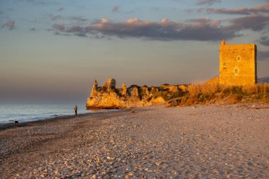 Tyrhenian kumsalı (Akdeniz) denizi. Kıyıdaki kayalıklardaki eski tarihi bina. Mavi akşam gökyüzü. Altın saatinde güneş ışığı. Kampofelice di Roccella, Sicilya, İtalya.