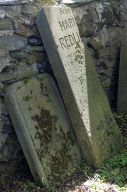 Stone fence. Jewish graves infront, Illuminated by sunlight. Old cemetery from 17. century in the former ghetto. Usov, Moravia (Morava), Czech republic. clipart