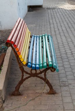 Yol kenarındaki bankta. LGBTIQ sembolü olarak, paslı metal taban ve gökkuşağı renklerinde bankın renkli ahşap çizgileri. Santa, Lanzarote, Kanarya Adaları, İspanya.