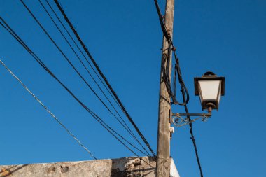 Yıpranmış tahta bir direğin üzerindeki sokak fenerinin klasik stili. Bir sürü kablo. Parlak mavi gökyüzü. Lanzarote, Kanarya Adaları, İspanya.