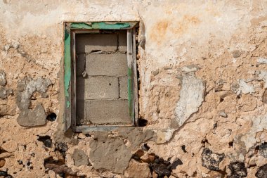 Terk edilmiş bir evin dış cephesi soyulmuş. Eskiden yeşil olan pencere çerçevesi şimdi camsız ve duvarlı. Güneşli bir gün. Caleta del Sebo, La Graciosa, Kanarya Adaları, İspanya.