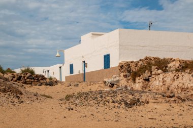 Geleneksel beyaz yüzlü köy evleri. Trafik yok, bütün sokaklar kumla kaplı. Kışın bulutlu bir gökyüzü. Caleta del Sebo, La Graciosa, Kanarya Adaları, İspanya.