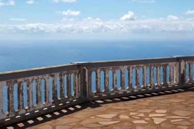 Yıpranmış kar maskesi ve taş zemini olan bir teras. Atlantik Okyanusu 'na bakış açısı. Baharda beyaz bulutlu mavi gökyüzü. Ponta do Pargo, Madeira, Portekiz.