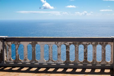 Yıpranmış kar maskesi ve taş zemini olan bir teras. Atlantik Okyanusu 'na bakış açısı. Baharda beyaz bulutlu mavi gökyüzü. Ponta do Pargo, Madeira, Portekiz.