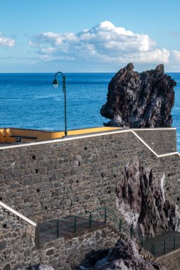 Atlantik Okyanusu 'na bir iskele olarak taş köprü. Beyaz bulutlu mavi gökyüzü. Ponta do Sol, Madeira, Portekiz.