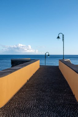 Atlantik Okyanusu 'na bir iskele olarak taş köprü. Beyaz bulutlu mavi gökyüzü. Ponta do Sol, Madeira, Portekiz.
