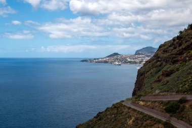 View on the calm water of Atlantic ocean from a mountain on the coast. Blue sky with white clouds in the spring. Canico, Madeira, Portugal. clipart