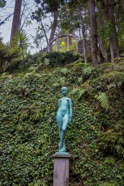 Eski bir kız heykeli. Arka planda taze yeşillik var. Tropik botanik bahçesi Monte Sarayı, Funchal, Madeira, Portekiz.