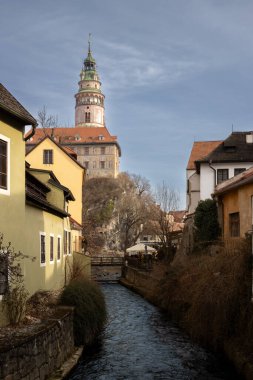 Kulesi olan Chateau Hradek. Vltava Nehri, kışın yeşilliklerle çevrili. Eski kasabanın evlerini. Açık beyaz bulutlu mavi gökyüzü. Cesky Krumlov, Çek Cumhuriyeti.