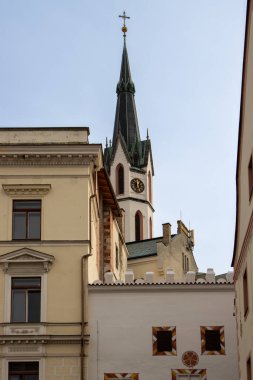 Eski şehirdeki evlerle çevrili tepede Gotik Aziz Vitus kilisesi haçı olan bir kule. Mavi kış gökyüzü. Cesky Krumlov, Çek Cumhuriyeti.