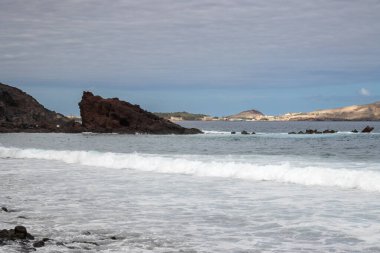 Kışın rüzgarlı bir günde dalgalı Atlantik Okyanusu. Kayalar ortada ve arka planda. Bulutlu gökyüzü. El Burrero, Las Palmas, Gran Kanarya, Kanarya Adaları, İspanya.