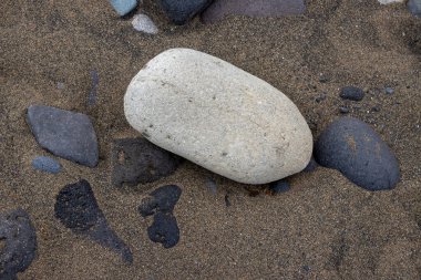 Sarı ve koyu volkanik kumların yapısı soyut dokular yaratıyor, çakıl taşlarıyla birlikte. El Burrero, Las Palmas, Gran Kanarya, Kanarya Adaları, İspanya.