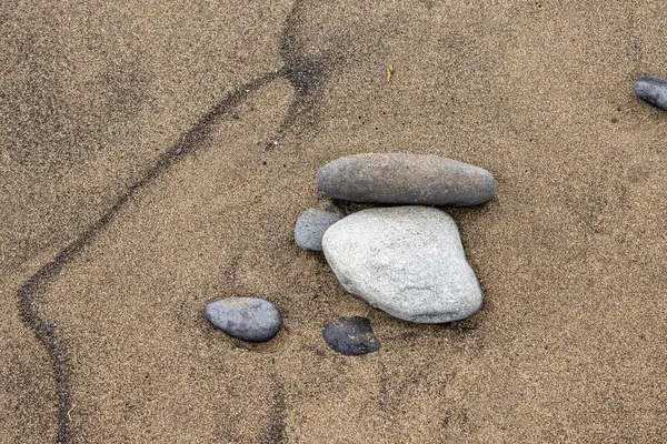 Sarı ve koyu volkanik kumların yapısı soyut dokular yaratıyor, çakıl taşlarıyla birlikte. El Burrero, Las Palmas, Gran Kanarya, Kanarya Adaları, İspanya.
