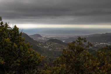 Adanın orta kesimindeki bir dağdan görüntü. Taze yeşillik ve bir sürü ev. Atlantik Okyanusu ve bulutlu gökyüzü. Lomo la Vega, Las Palmas, Gran Canaria, Kanarya Adaları, İspanya.
