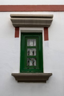 Yeşil çerçeveli küçük bir pencere ve evin beyaz cephesinde kırmızı detaylar. Puerto de Mogan, Las Palmas, Gran Canaria, Kanarya Adaları, İspanya.