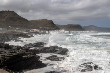 Atlantik Okyanusu 'nun kayalık kıyıları ve rüzgarlı kış günlerinde büyük dalgalar. Arka planda dağlar. Las Palmas, Gran Canaria, Kanarya Adaları, İspanya.
