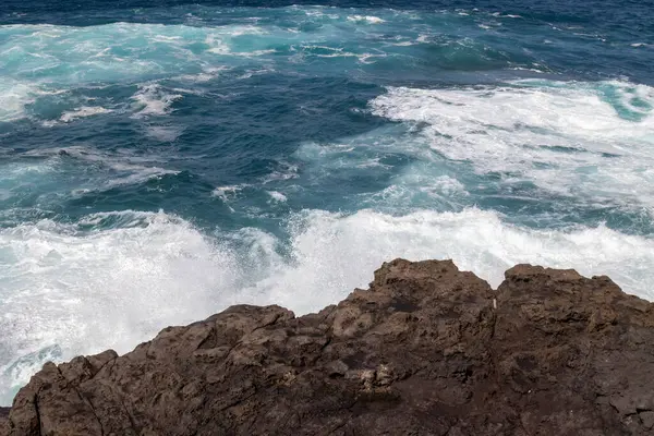 Atlantik Okyanusu kıyısındaki volkanik kahverengi kayalar. Kış rüzgarlı bir günde yoğun dalgalar. Galdar, Las Palmas, Gran Kanarya, Kanarya Adaları, İspanya.