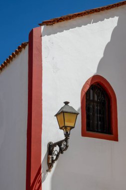 Aziz Rita (Iglesia de Santa Rita) kilisesinin köşesi. Beyaz cephe ve kırmızı detaylar. Geleneksel fener ve çapraz gölge penceresi. Mavi gökyüzü. Gran Kanaryası, Kanarya Adaları, İspanya.