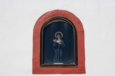 Aziz Rita Kilisesi 'nin (Iglesia de Santa Rita) üzerinde haçlı Aziz Rita heykeli bulunan kırmızı çerçeveli parlak beyaz duvarı. Ojos de Garza, Las Palmas, Gran Canaria, Kanarya Adaları, İspanya.