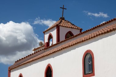 Beyaz Santa Rita Kilisesi (Iglesia de Santa Rita) kırmızı detaylarla. Parlak mavi gökyüzü. Çan kulesi ve haç. Ojos de Garza, Las Palmas, Gran Canaria, Kanarya Adaları, İspanya.
