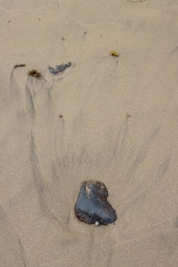 Gelgitten sonra Atlantik Okyanusu sahilinde sarı kum. Volkanik kumdaki çakıl taşları ve koyu renkler. Playa del Cabron, Las Palmas, Gran Canaria, Kanarya Adaları, İspanya.