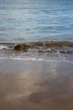 Akşamın erken saatlerinde kumsalda, güneş batarken. Gelgit çizgisi ve güneş ışığı, gökyüzü ve bulutların yansıması. Playa del Cabron, Las Palmas, Gran Canaria, Kanarya Adaları, İspanya.