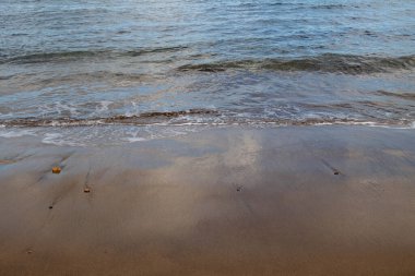 Akşamın erken saatlerinde kumsalda, güneş batarken. Gelgit çizgisi ve güneş ışığı, gökyüzü ve bulutların yansıması. Playa del Cabron, Las Palmas, Gran Canaria, Kanarya Adaları, İspanya.