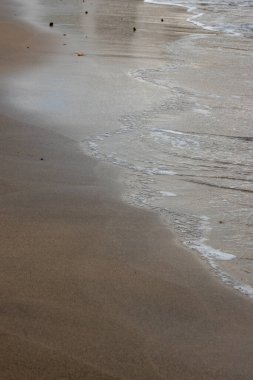 Akşamın erken saatlerinde kumsalda, güneş batarken. Gelgit çizgisi ve güneş ışığı, gökyüzü ve bulutların yansıması. Playa del Cabron, Las Palmas, Gran Canaria, Kanarya Adaları, İspanya.