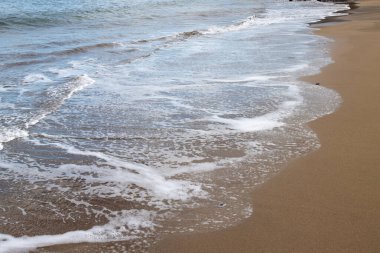 Akşamın erken saatlerinde kumsalda, güneş batarken. Gelgit çizgisi ve güneş ışığı, gökyüzü ve bulutların yansıması. Playa del Cabron, Las Palmas, Gran Canaria, Kanarya Adaları, İspanya.