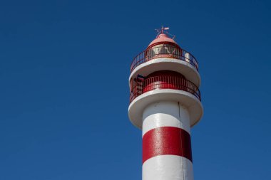 Deniz feneri (Faro de Sardina) kırmızı ve beyaz çizgili, geleneksel tarzda. Mavi gökyüzü. Atlantik Okyanusu kıyısında. Galdar, Las Palmas, Gran Kanarya, Kanarya Adaları, İspanya.