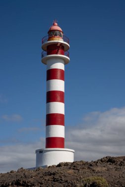 Deniz feneri (Faro de Sardina) kırmızı ve beyaz çizgili, geleneksel tarzda. Mavi gökyüzü. Atlantik Okyanusu kıyısında. Galdar, Las Palmas, Gran Kanarya, Kanarya Adaları, İspanya.