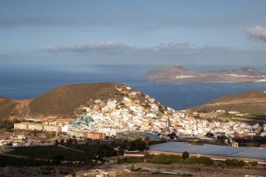 Adanın kuzeyinde bir dağdan (La Montana de Arucas) manzara. Evler ve tepeler. Beyaz bulutlu mavi gökyüzü. Arucas, Las Palmas, Gran Canaria, Kanarya Adaları, İspanya.