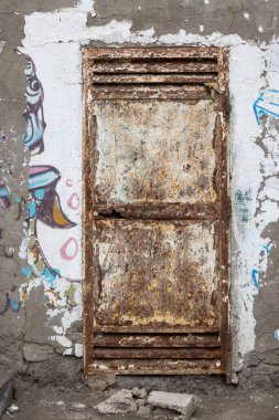 Terk edilmiş bir tatil köyünün beton duvarında kalan graffiti lekeleri var. Paslı kapalı kapı. La Estrella, Las Palmas, Gran Canaria, Kanarya Adaları, İspanya.