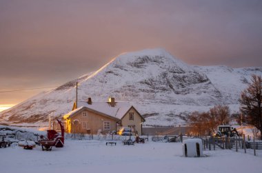Kutup günbatımında bahçeli bir ev. Arkadaki görkemli dağ. Renkli gökyüzü. Sandsoy, Norveç.