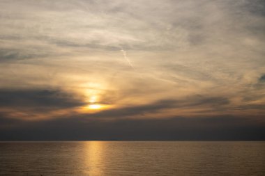 Baharın sonlarında renkli bulutlar. Bulutlu gökyüzü ve güneş ışığının yansımasıyla İyon denizi. Acharavi, Korfu, Yunanistan.