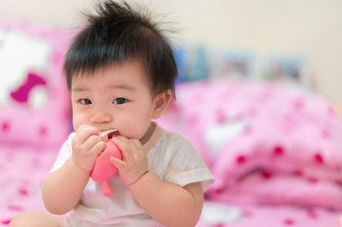 Asyalı küçük kız ipi ısırıyor, bebek ilk dişini çıkarıyor..