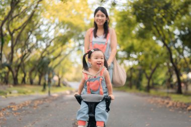 Asyalı anne kızıyla parkta geziyor, Mutlu aile kavramı..