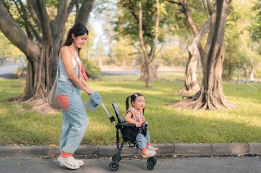 Asyalı anne kızıyla parkta geziyor, Mutlu aile kavramı..