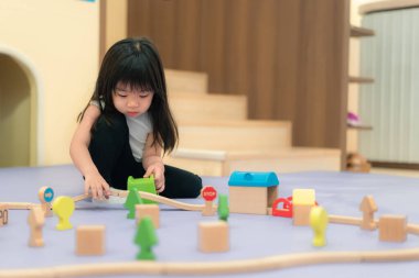 Genç Asyalı Kız Renkli Ahşap Yapı Blokları ve Oyuncak Figürleriyle Yaratıcı Oyun Oynuyor