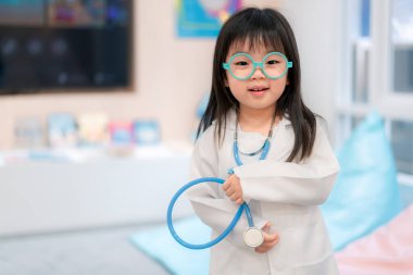 Little asian girl wearing a white coat playing doctor with holding a stethoscope in her hand. Perfect for themes related to education, creative play, and children's health. clipart