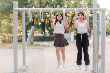 İki kadın salıncakta sallanıyor. Bir tanesi beyaz gömlek ve siyah etek giyiyor.