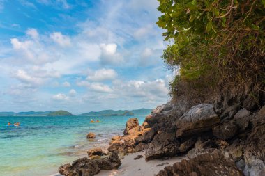 Berrak turkuaz su, kayalık formasyonlar ve yemyeşil ve parlak mavi gökyüzünün çerçevelediği kano oyuncularının yer aldığı güzel bir sahnenin tadını çıkarın..